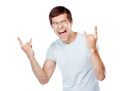 Young excited man wearing glasses and blue t-shirt showing horns hand gesture with both hands and happy screaming isolated on white background - joy conceptの写真素材