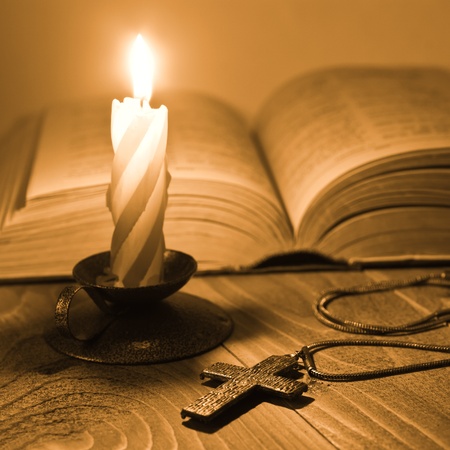 Metal cross lying on the table by candlelight Metal cross lying on the table by candlelight