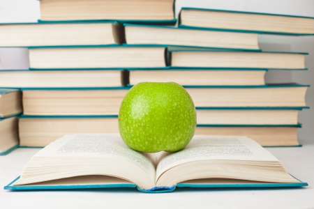 Green apple lying on an open bookの写真素材