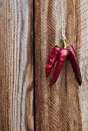 Dried chili peppers hanging on a wooden wall backgroundの写真素材