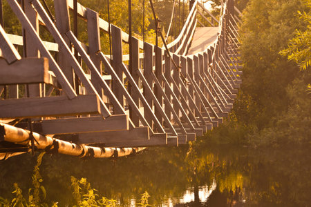 Suspended footbridge in the golden sunlightの写真素材