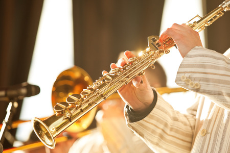 Hands of musician playing the soprano saxophone in golden sunlightの写真素材