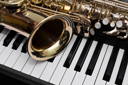Fragment of the saxophone lying on the piano keysの写真素材