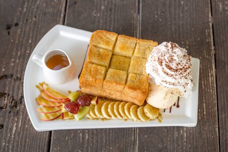 Honey Toast with vanilla ice-cream, grape, kiwi, banana, apple and whip creamの写真素材