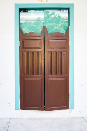 Wood door in front of the glass gate that was closed at the entrance of building in Thailandの写真素材
