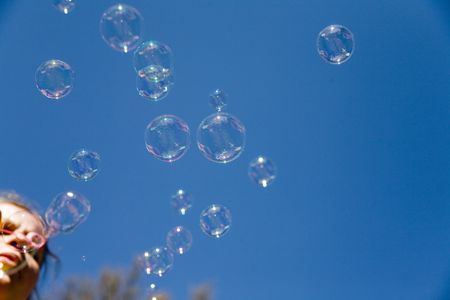 woman blowing bubbles over the blue sky