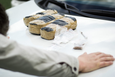 Detained criminal on the hood of a car with packets of drugs. Drugs, the fight against drug addiction.の写真素材