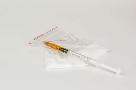 Syringe with drug and cooked heroin. Cocaine in the package. Isolated on white background.の写真素材