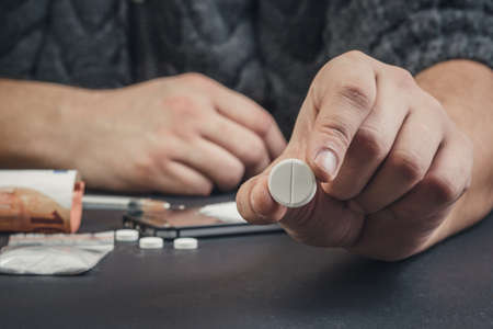 A drug addict or a drug dealer holding a pill with the drug.の写真素材