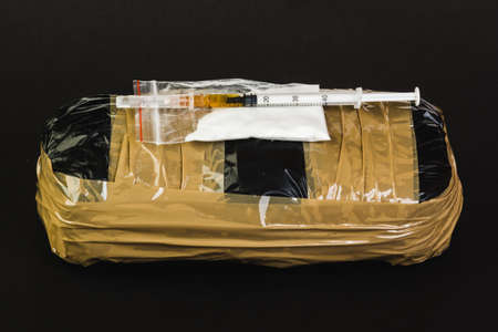 Syringe with drug and cooked heroin. Cocaine in the package. Isolated on a black background.の写真素材