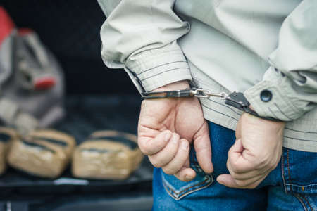 A man in handcuffs detained the transportation of drugs.の写真素材