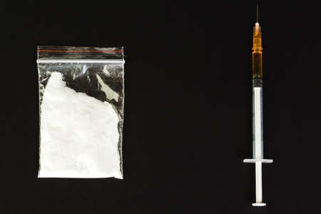 Syringe with drug and cooked heroin. Cocaine in the package. Isolated on a black background.の写真素材