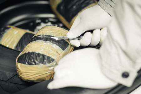 A packet of drugs was found in the spare wheel of the car. Drugs, the fight against drug crime.の写真素材
