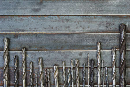 A set of used drill bits for metal,wood and other materials. On the old, rusted metal background.の写真素材