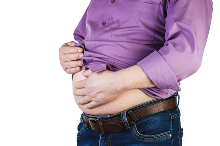 Excess body weight of a man with his hands touching fat on his stomach is the concept of obesity. Not the right food.の写真素材
