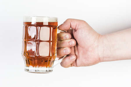 A glass of beer in a hand isolated on white background.の写真素材