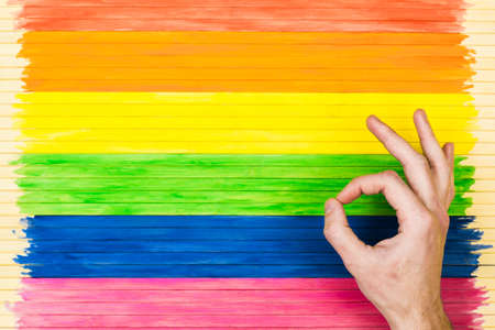 People, gay parade, gesture and homosexual concept, showing symbols on the background of the rainbow flag strip.の写真素材