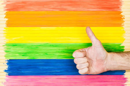 People, gay parade, gesture and homosexual concept, showing symbols on the background of the rainbow flag strip.の写真素材