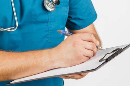 Male doctor with stethoscope writing on clipboard message or board, on white background