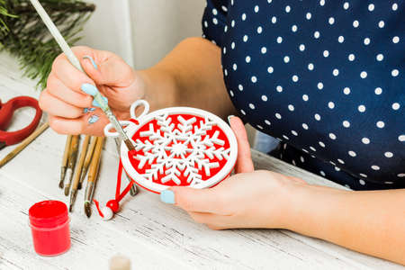 Christmas decorations, balls, toys and gift boxes on an old wooden board. Female hands make...