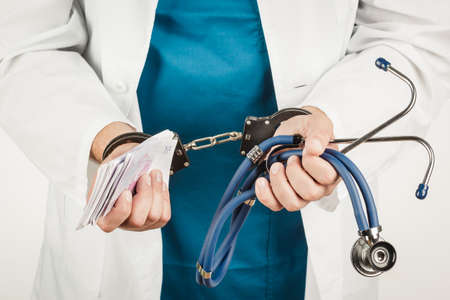Doctor with a stethoscope and euro-banknotes and handcuffs. Crimeの写真素材