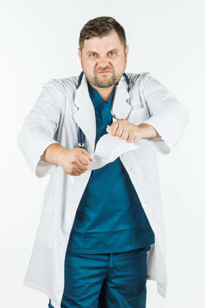 A portrait of a male doctor, tearing and tearing paper. Bad diagnosis, wrong treatment, lost, upset. on a white backgroundの写真素材