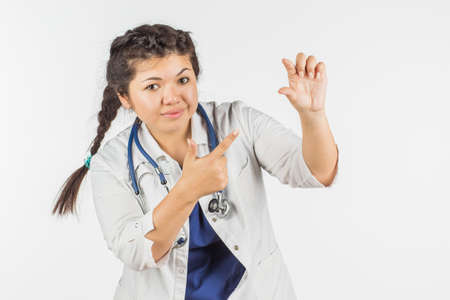 a female doctor in a white coat and a stethoscope showing the size of something. People and the...