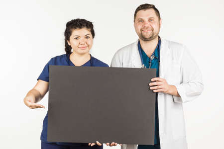 Young female doctor and male doctor shows up on an empty billboard, on a white background.の写真素材