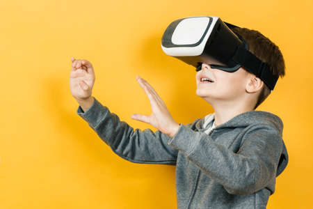 Boy with a headset of virtual reality. Innovative technology. On an orange background.