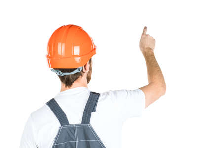 A construction man stands with his back and shows his hand. Repair and construction. Isolated over white backgroundの写真素材