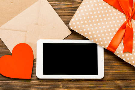 Digital tablet with gifts and hearts on wooden table. View from above. Valentines Day conceptの写真素材