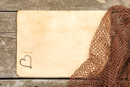 Fishing gear - fishing, hooks, fishing net, old sheet of paper on a wooden background.の写真素材