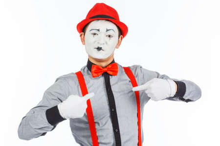 Portrait of a man, actor, pantomime, looking at the camera and showing a finger on himself. Standing in front of white backgroundの写真素材
