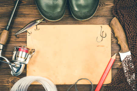 Fishing gear - fishing, fishing, hooks and baits, an old sheet of paper on a wooden background. Toned image.の写真素材