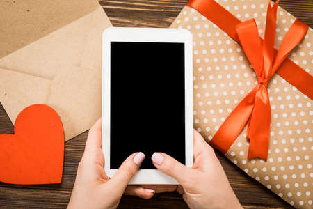 Digital tablet with gifts and hearts on wooden table. View from above. Valentines Day concept