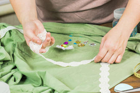 A woman is making jewelry, a home workshop. Female hands that create an accessory with beads and...