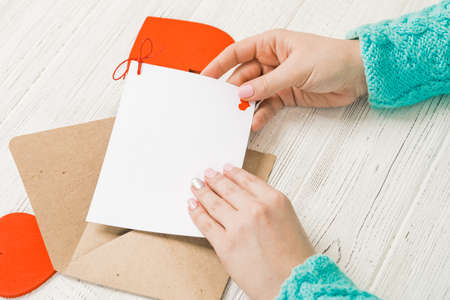 Hand of girl writing love letter on Saint Valentines Day. Handmade postcard with red heart shaped figure. 14 February holiday celebration. Valentine day concept with copy space.の写真素材