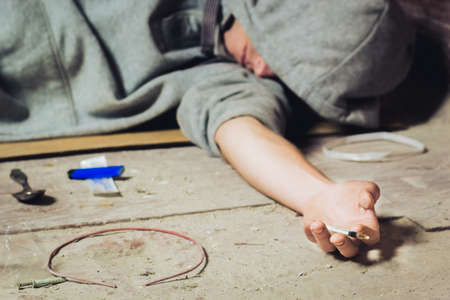 Hand addict and syringe with heroin lying on the floor. The concept of anti drugs. male drug addict hand, drugs narcotic syringe.の写真素材