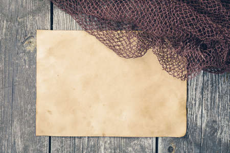 Fishing tackle - fishing net, old sheet of paper on a wooden background.の写真素材