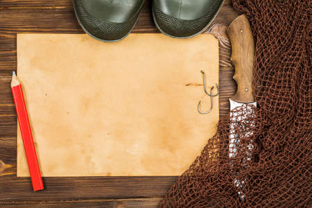 Fishing gear - fishing, fishing, hooks and baits, an old sheet of paper on a wooden background.の写真素材