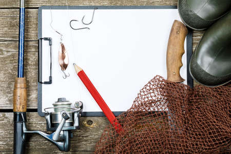 Fishing gear - fishing, pencil, hooks, boots, wooden background.の写真素材