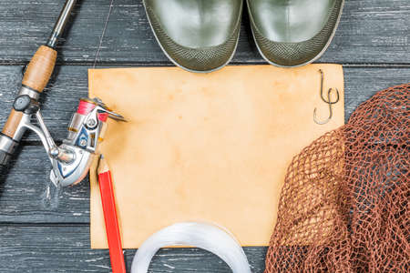 Fishing gear - fishing, fishing, hooks and baits, an old sheet of paper on a wooden background.の写真素材