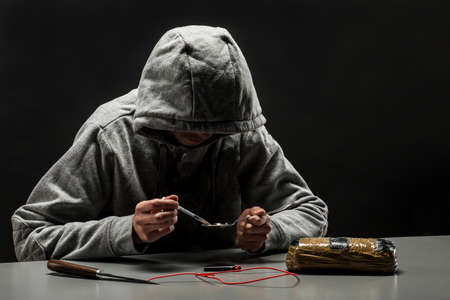 man is a drug addict sitting at the table makes drugs. The concept of social problems of drug...