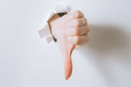 girl hand breaks white paper and shows a gesture.の写真素材