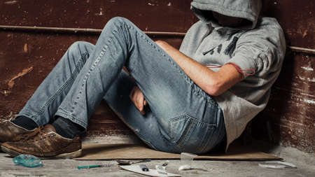A man is a drug addict with a syringe using drugs lying on the floor. The concept of anti drugs. male drug addict, drug syringe.の写真素材