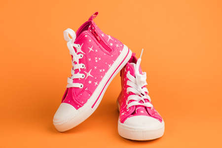 Red children's shoes. On orange backgroundの写真素材