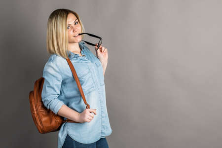 Portrait of a girl with a backpack on a gray background