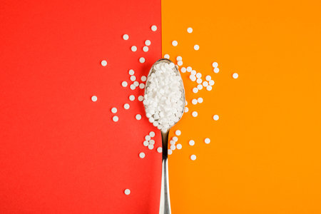 Sugar-replacing tablets spoon on orange and red background.