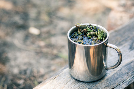 Mug with a hot drink on a wooden stump in the open air. Morning at the campsite.