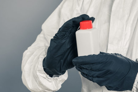 A medical scientist or a policeman wearing protective clothing holds a plastic tube in his hand. The...